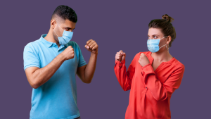 Playful married couple in boxing stance, wearing matching face masks—visual metaphor for defensiveness in marriage communication.